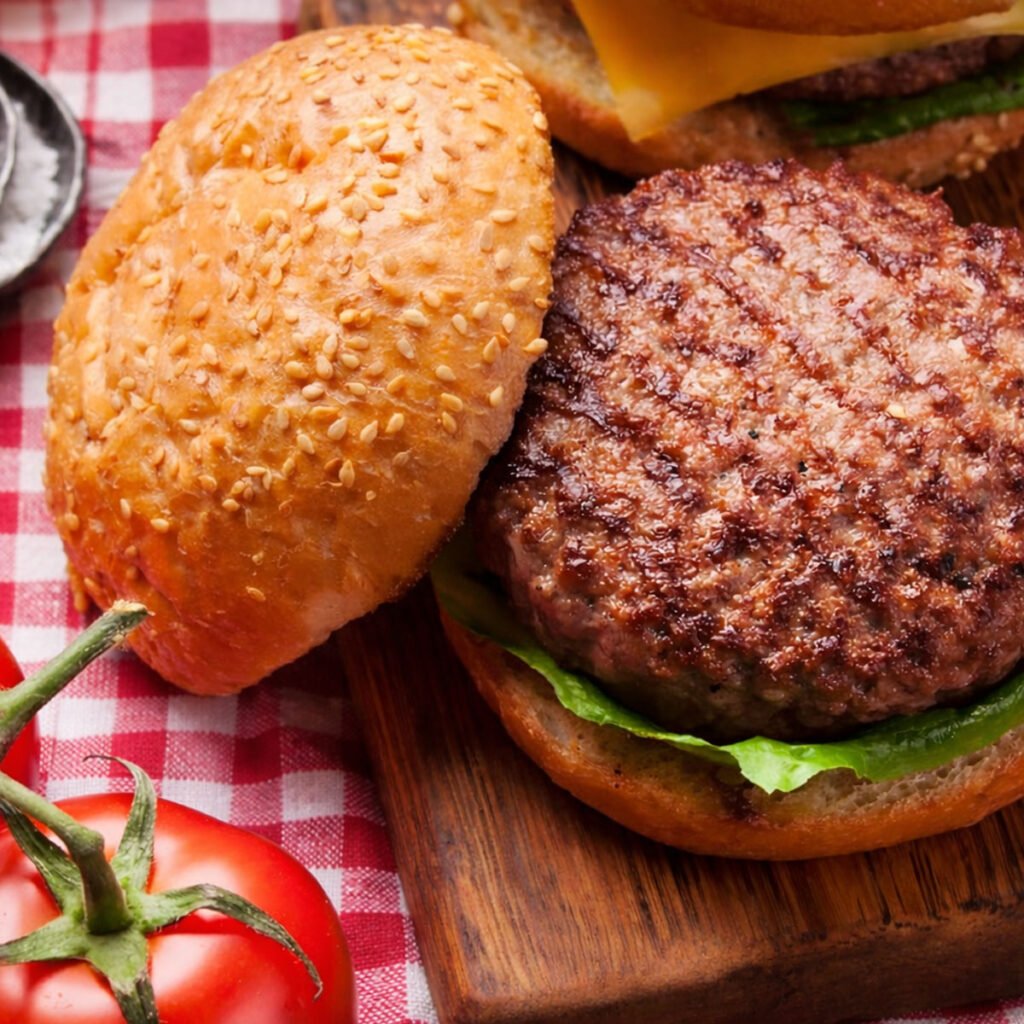 Hamburguesa casera en kamado con pan de patatas sobre tabla rústica