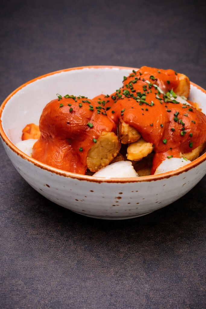 Patatas bravas caseras con salsa roja durante la preparación