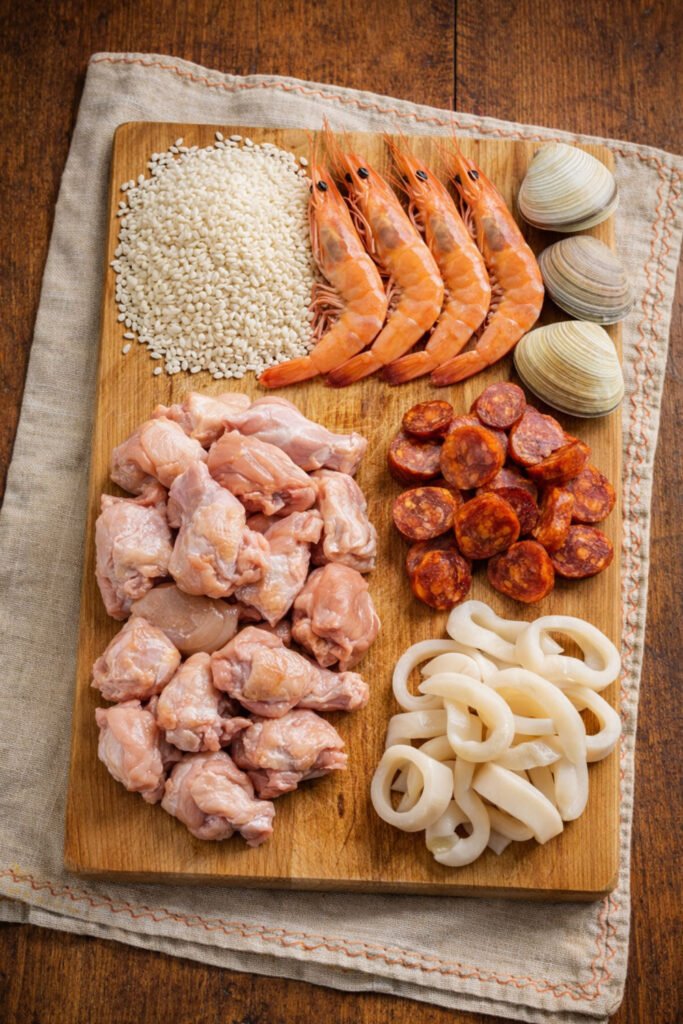 Ingredientes crudos para paella mixta al kamado sobre tabla de madera y mantel rústico