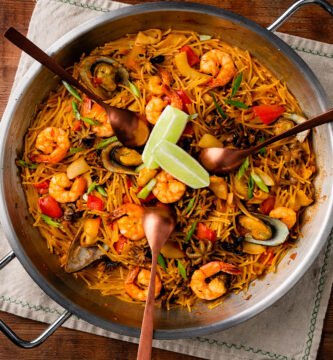 Fideuá de mariscos cocinada en kamado con gambas, mejillones y fideos dorados sobre mesa rústica