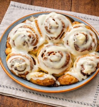 Rollitos de canela glaseados recién horneados al kamado sobre mesa rústica