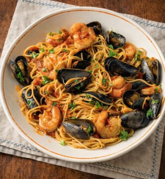 Spaghetti con mariscos cocinados al kamado sobre mesa rústica de roble