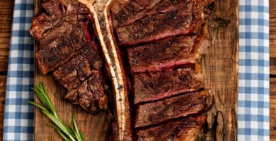 T-bone steak en kamado servido sobre tabla de madera con ensalada de patatas y judías verdes