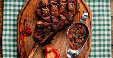 Tomahawk de ternera en kamado con alubias rojas servido sobre tabla de madera